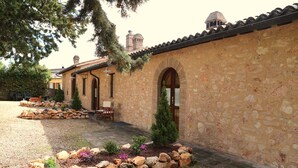 A stone building with arched doorways and a tiled roof. - Corte Fratini Residenza D'Epoca (Trevi)
