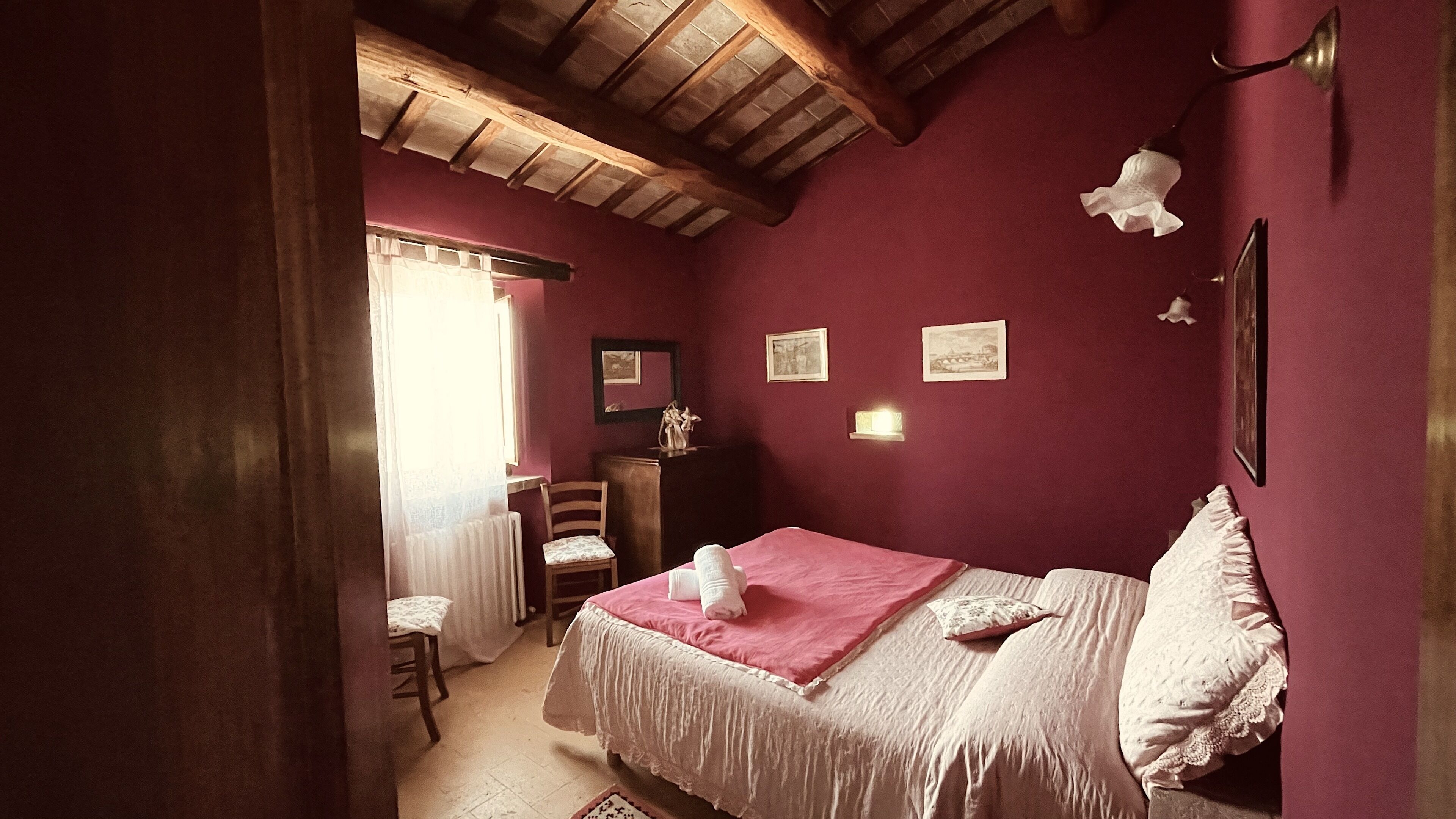 A bedroom with a bed, a chair, a dresser, and a window with curtains.