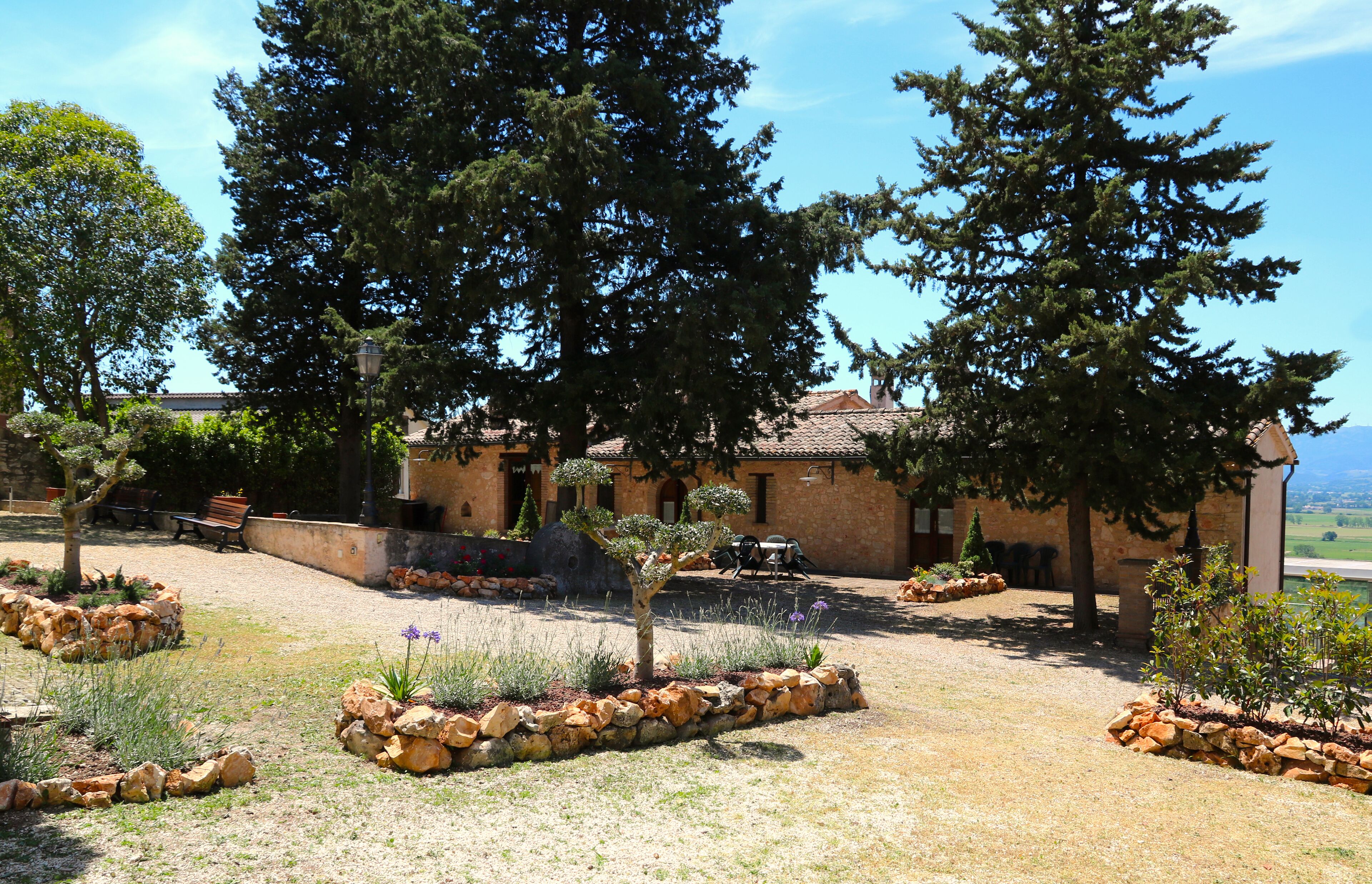 Un edificio rústico con un patio interior, rodeado de árboles grandes y senderos de piedra.