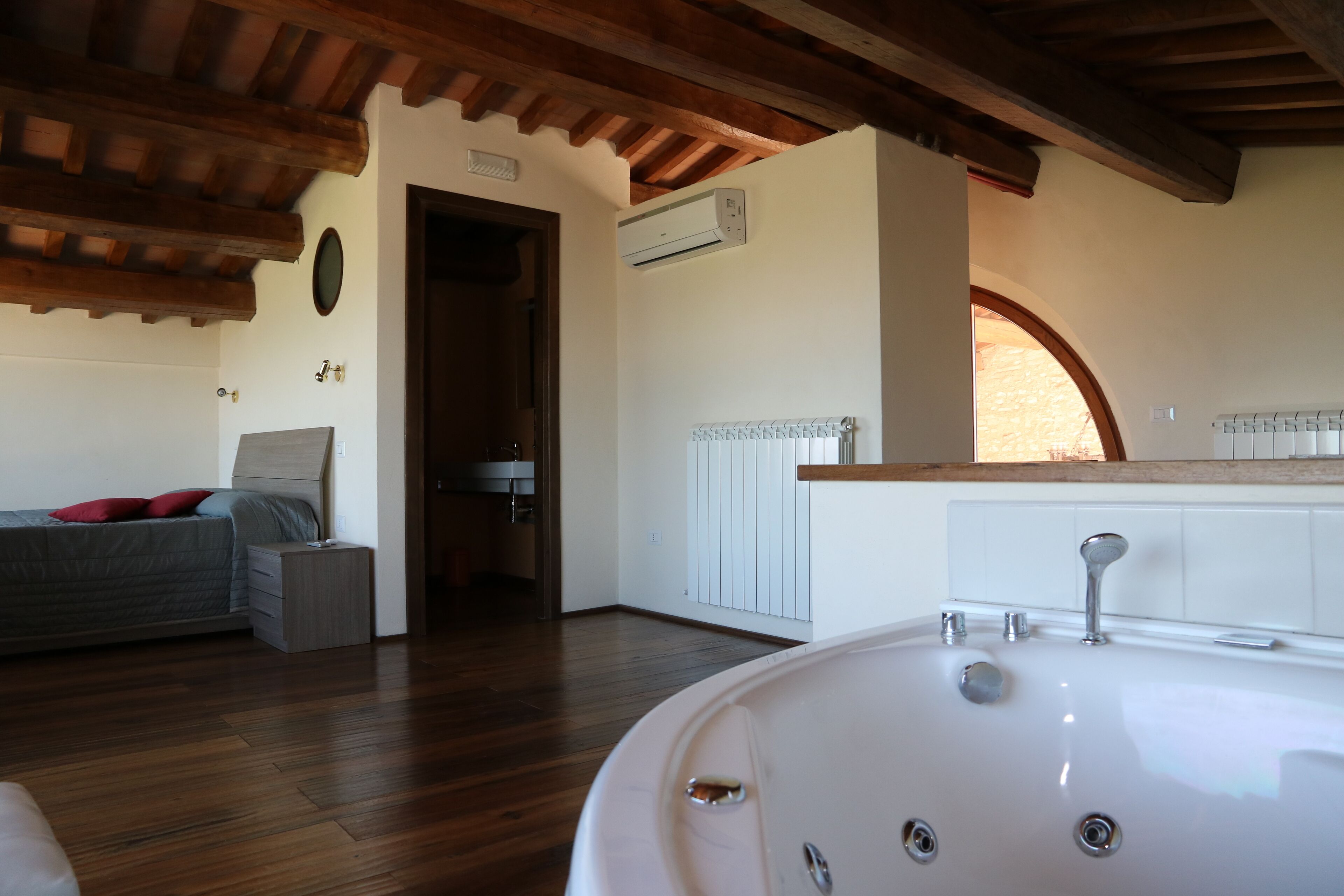 Un dormitorio con techo de madera, una cama, una mesita de noche y un baño con bañera.