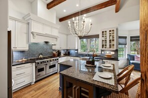 A kitchen with white cabinets, a granite countertop, a chandelier, and a large window. - Luxury 4BD on Kiawah w/ Chef's Kitchen, Private Pool + Hot Tub (Kiawah Island)