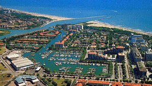 Vista aerea di una città costiera con un porto turistico, zone residenziali e una spiaggia.