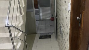 Een trap die leidt naar een kamer met een behangpatroon en een deur met een hendel.