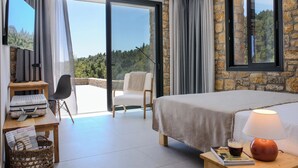 A bedroom with a bed, a desk, a chair, a lamp, and a view of the outdoors. - The Mavrolitharo Residence, new stone built villa.  (Chalkidiki)
