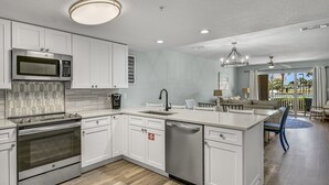 A modern kitchen with white cabinetry, stainless steel appliances, and a central island. - Completely Remodeled, 2 Kings, Bunkroom, Beach Service  (Miramar Beach)