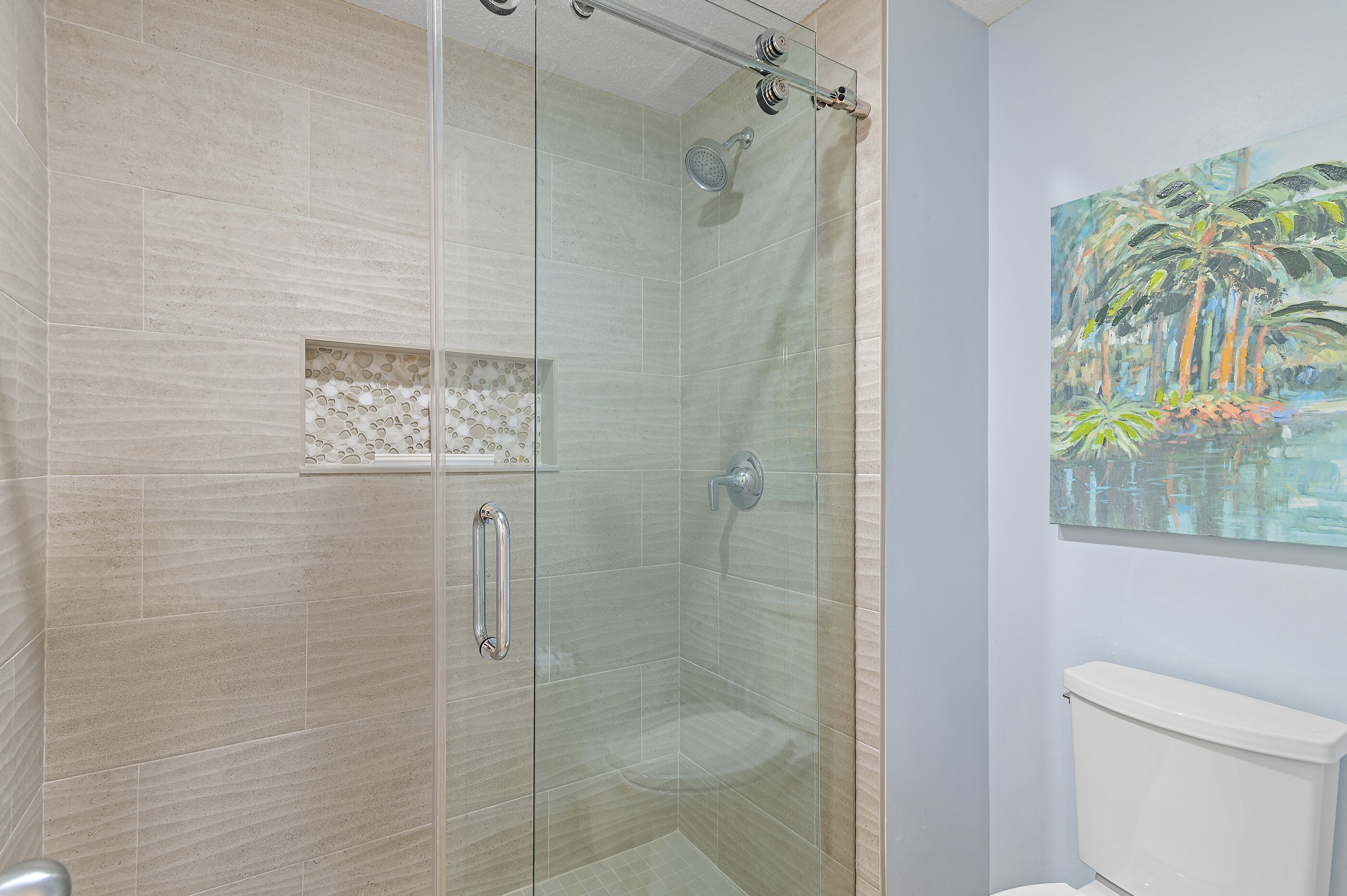 Une salle de bain moderne avec une douche à parois de verre, des toilettes et un élément décoratif mural.