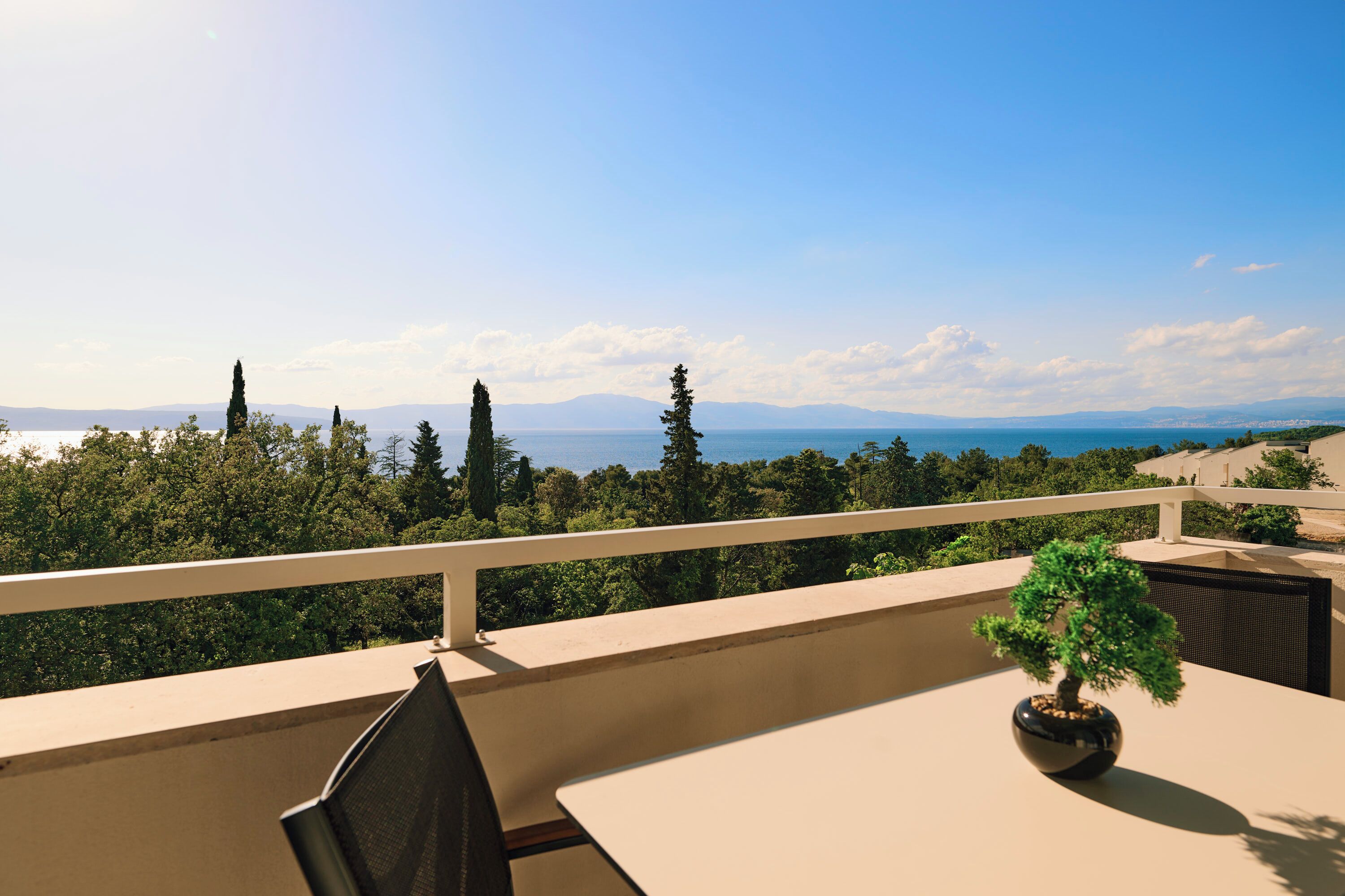 Un balcon offrant une vue sur un paysage montagneux et un plan d’eau.