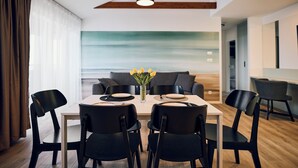 A modern dining area with a wooden ceiling, a table set for four, and a view of the ocean through a large window. - Malinska Green Apartments (Malinska-Dubasnica)