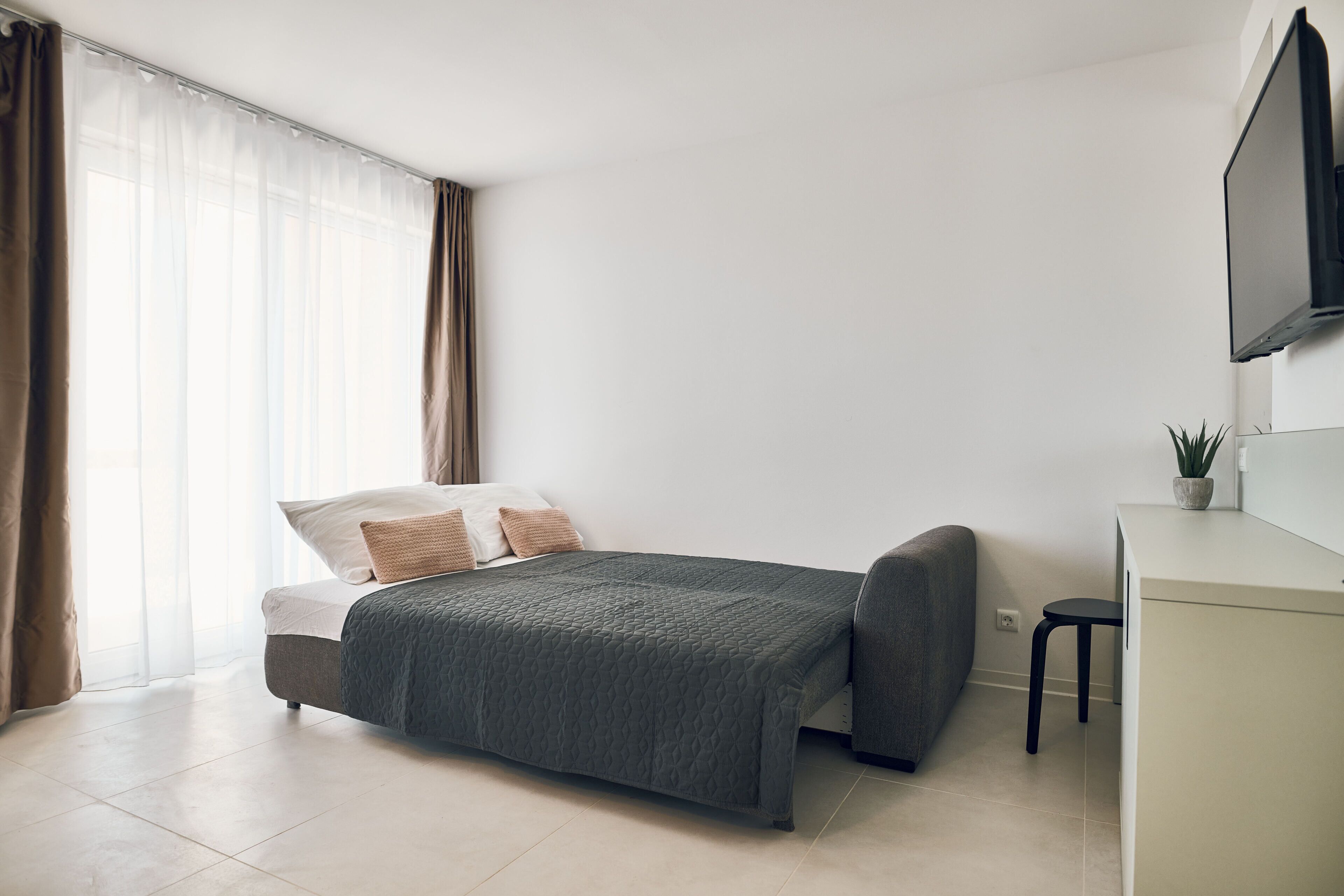 Une chambre à coucher moderne avec un lit, un bureau et un téléviseur.