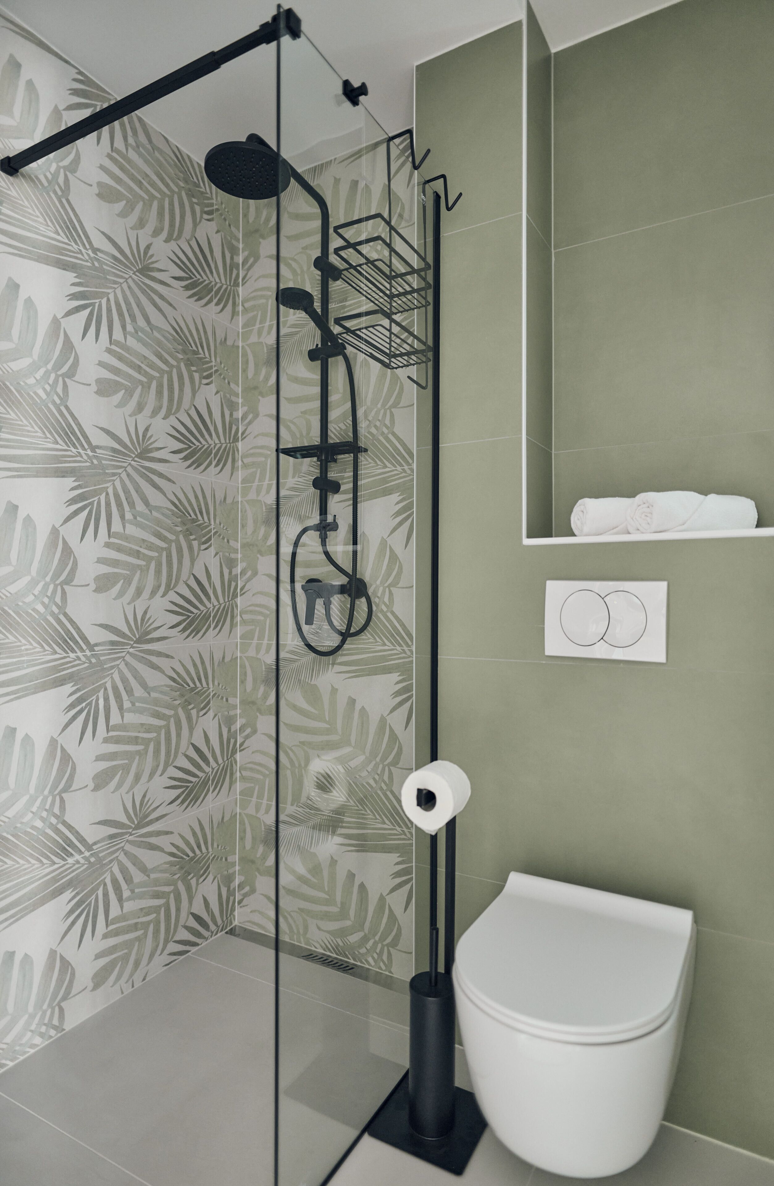 A modern bathroom with a shower, toilet, and a towel rack.