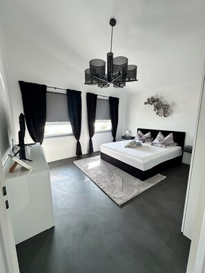 Ein modernes Schlafzimmer mit einem großen Bett, einem Schreibtisch und einer Kronleuchter.