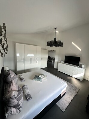 Une chambre moderne avec un grand lit, une télévision et une armoire.