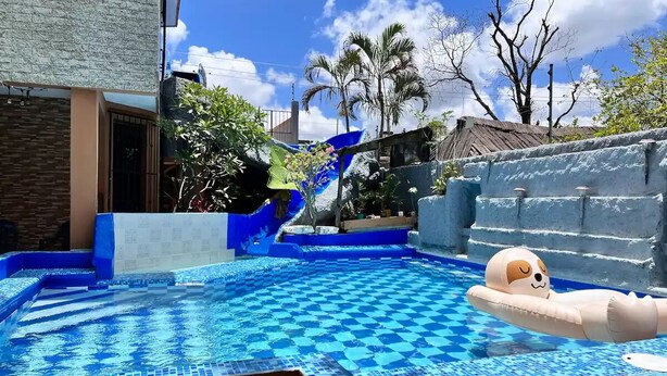 A swimming pool with a blue and white checkered pattern, a slide, and a dog float. - Casa Real con tobogán de agua privada (San Miguel de Cozumel)