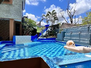 A swimming pool with a blue and white checkered pattern, a slide, and a dog float. - Casa Real con tobogán de agua privada (San Miguel de Cozumel)