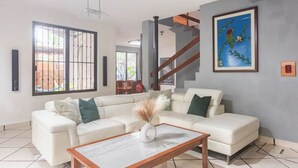 A modern living room with a white sofa, a wooden coffee table, and a painting on the wall. - Casa Real con tobogán de agua privada (San Miguel de Cozumel)