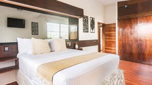 A bedroom with a large bed, a wooden wardrobe, a flat-screen TV, and a large mirror. - Casa Real con tobogán de agua privada (San Miguel de Cozumel)