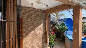 A covered outdoor area with a stone wall, a metal gate, and a blue water feature. - Casa Real con tobogán de agua privada (San Miguel de Cozumel)