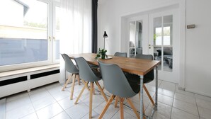 Un comedor con una mesa de madera, sillas grises y una planta en maceta.