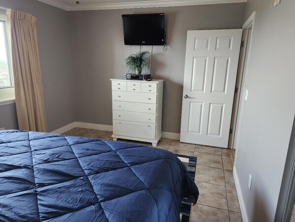 Un dormitorio con cama, cómoda, televisor y puerta.