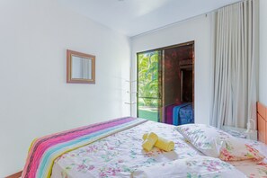 Een slaapkamer met een bed, een spiegel en uitzicht op het exterieur.