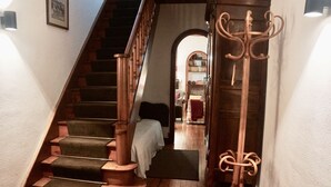 A wooden staircase with a carpeted landing and a coat rack.