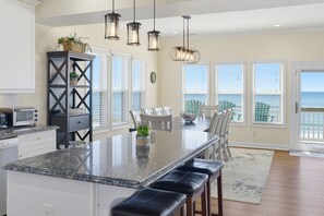 A kitchen with a large island, a dining area with a view, and a built-in bookshelf. - Experience beachfront luxury at 1128 Sweet Carolina Discounts for open 2026 dates (North Topsail Beach)