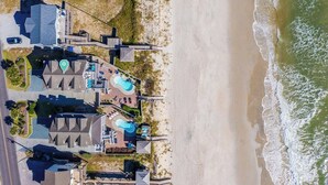 An aerial view of a coastal property with multiple buildings, a beach, and a swimming pool area.