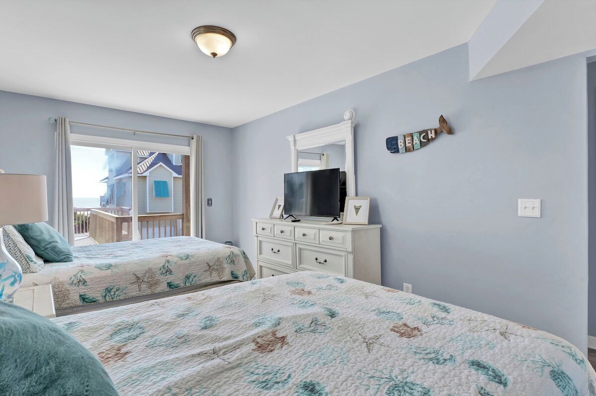 Un dormitorio con dos camas, un aparador, un televisor y una ventana con vista a un balcón.