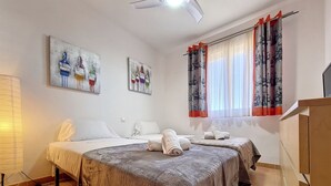 Quarto de hotel com duas camas, um ventilador de teto e obras de arte nas paredes.