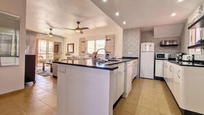 Uma cozinha moderna com ilha central, armários brancos e backsplash em padrão herringbone.