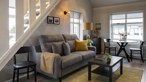 A modern living room with a grey sofa, a coffee table, and a staircase. - Keflavik's Ray of sunshine Hafnargata (Reykjanesbær)