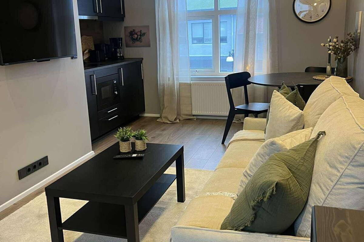 A modern living room with a sofa, a coffee table, and a TV mounted on the wall.