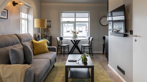 A modern living room with a grey sofa, a coffee table, and a dining area with a table and chairs. - Keflavik's Ray of sunshine Hafnargata (Reykjanesbær)