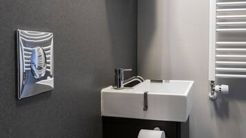 A modern bathroom with a white sink, dark cabinet, and a towel hanging on the wall.
