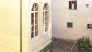Ein Innenhof mit einem Gebäude, das gewölbte Fenster und eine Stein-Fassade hat.