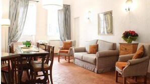 Ein Wohnzimmer mit Esstisch, Stühlen, einer Couch und einer Lampe.