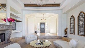 A spacious living room with a round coffee table, white sofas, and a fireplace. - Pristine Luxury Estate, Views, Sleeps 26, Heated Pool & Spa (Fountain Hills)