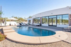 A modern house with a swimming pool, large windows, and outdoor seating.