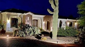 A house with a stone facade, arched windows, and a prominent cactus in the front yard. - Pristine Luxury Estate, Views, Sleeps 26, Heated Pool & Spa (Fountain Hills)