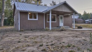 A small, single-story wooden cabin with a metal roof, a porch, and a door.