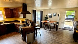 A spacious kitchen with wooden cabinets, a dining area with a table and chairs, and a compact refrigerator.