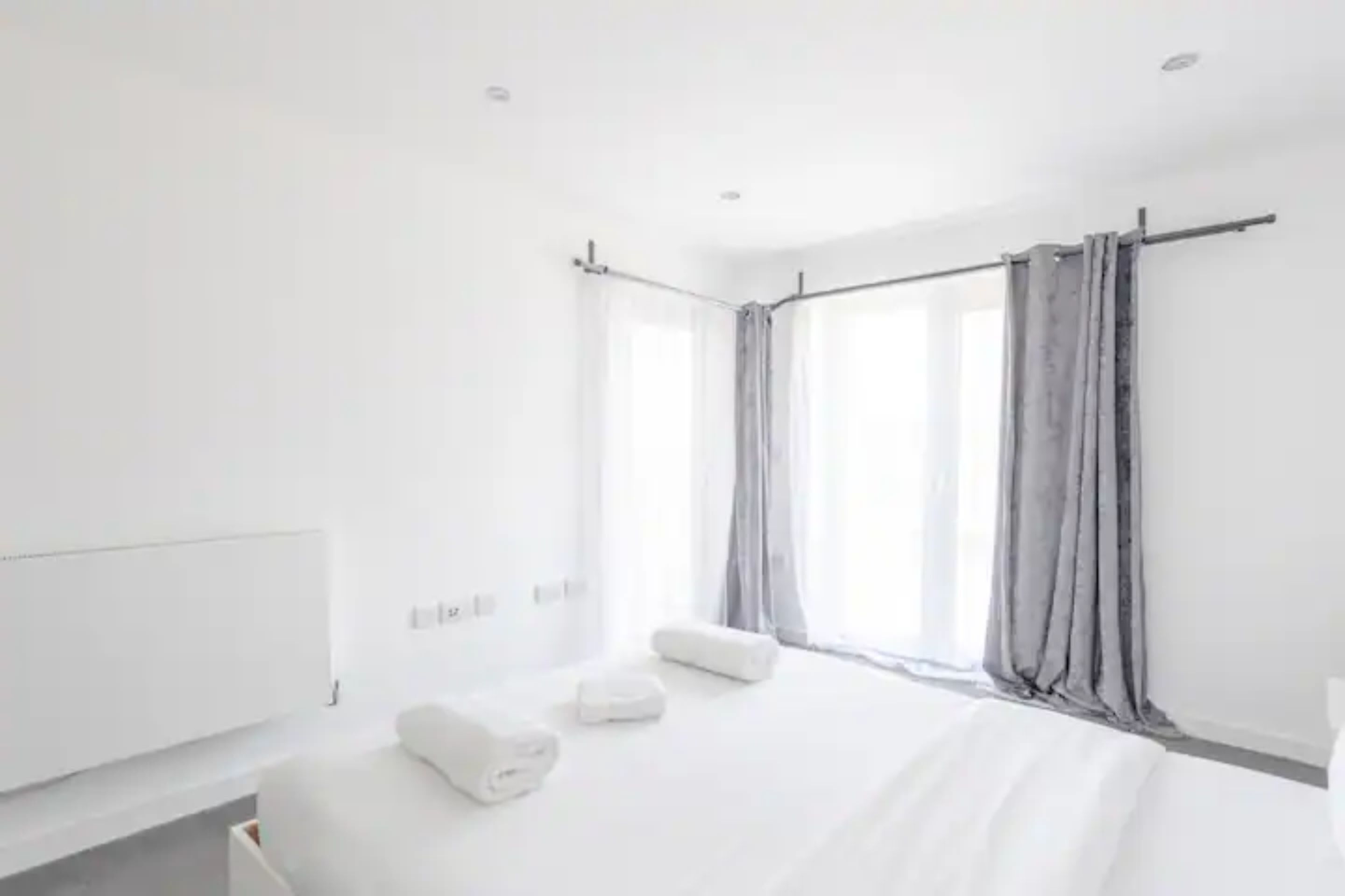 A modern hotel room with a large bed, a bedside table, and a window with curtains.