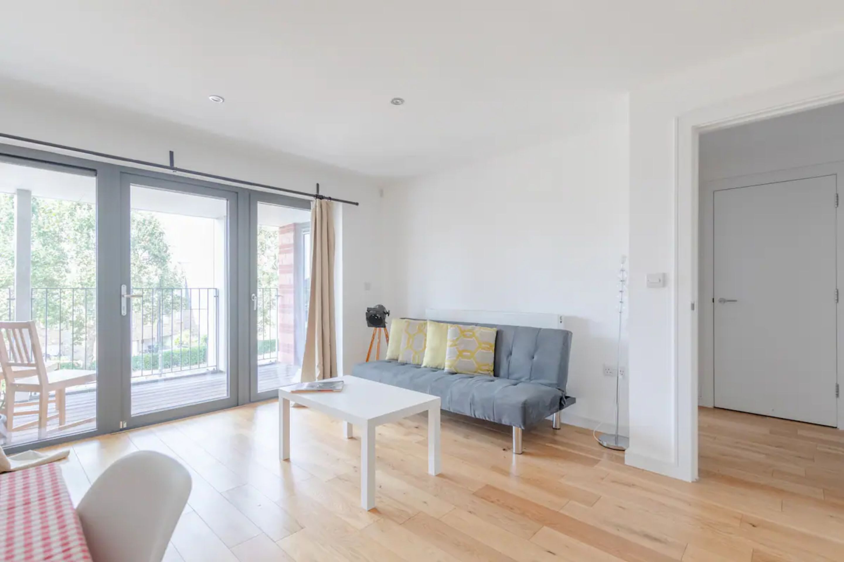 A modern living room with a sofa, a coffee table, and a sliding glass door leading to an outdoor area.