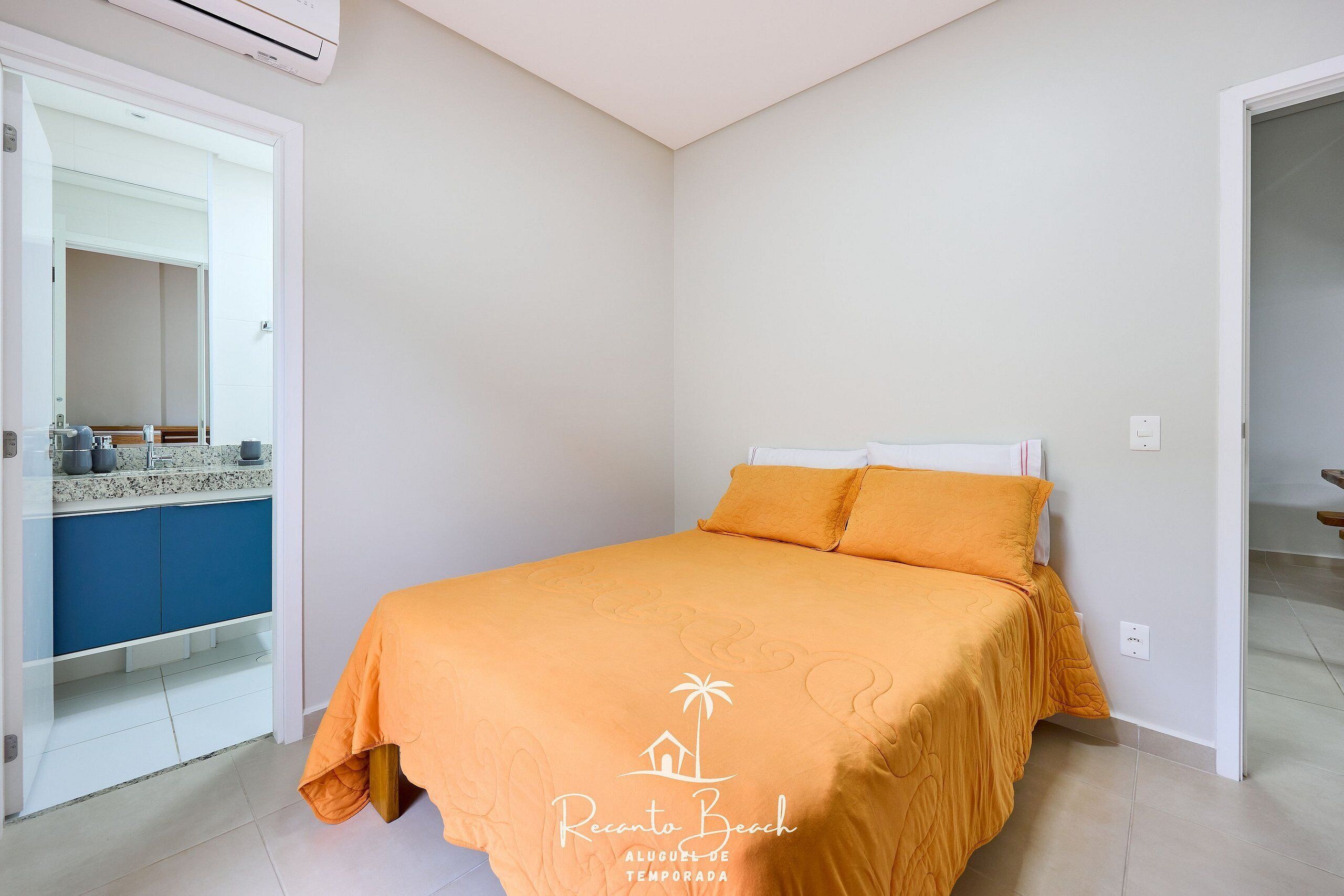 A bedroom with a bed, a wardrobe, and a bathroom visible through an open door.