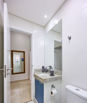 A modern bathroom with a white sink, a large mirror, and a toilet. - Sunset (Ubatuba)