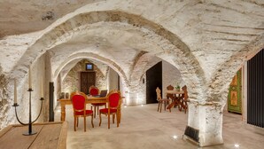 A dining area with a rustic stone ceiling, wooden tables, and red upholstered chairs. - Boutiquehotel Rattenberg (Rattenberg)