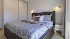 A modern bedroom with a large bed, a dark headboard, and two bedside tables. - Caci-C2 with Pool - istriensonne 0736 (Medulin)