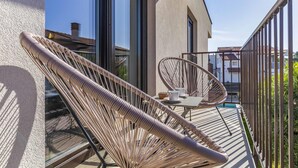 A balcony with a wicker chair and a table, overlooking a residential area. - Caci-C2 with Pool - istriensonne 0736 (Medulin)