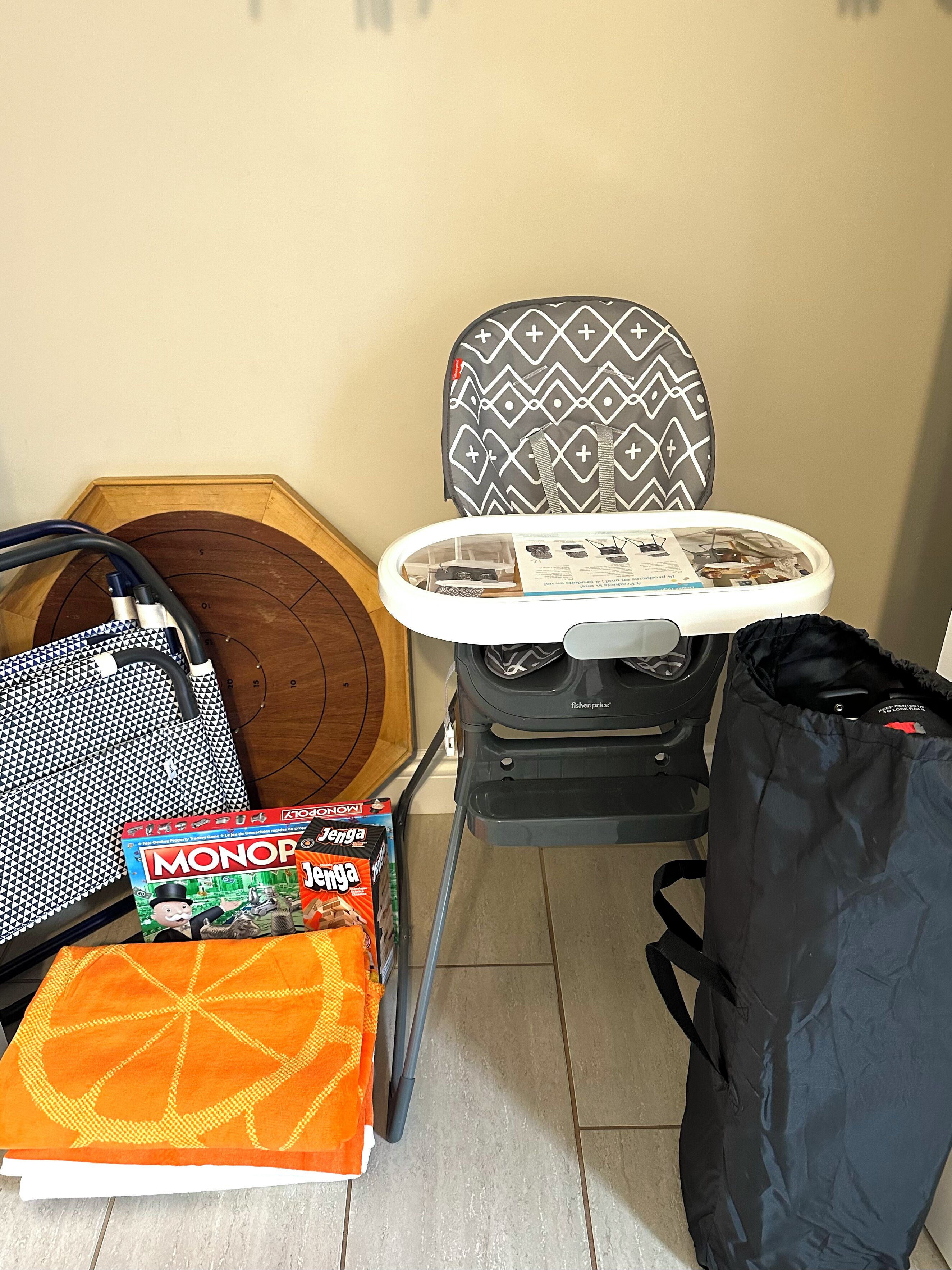 A room with a wooden floor, a patterned ironing board, a suitcase, and Monopoly game boxes.