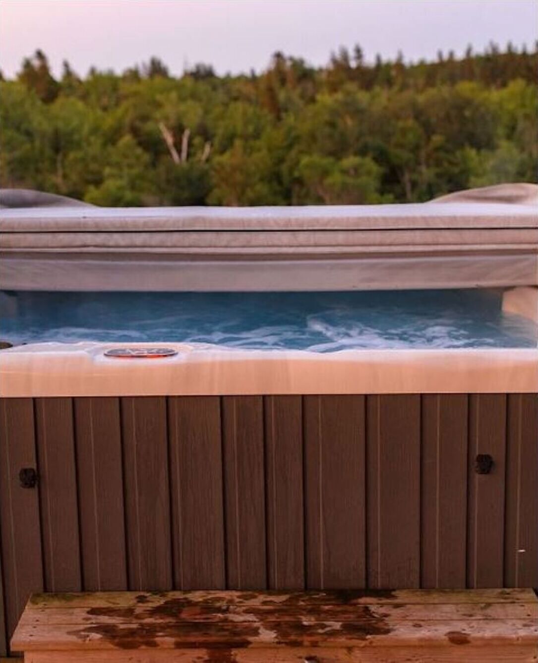 A hot tub with a wooden deck in front.
